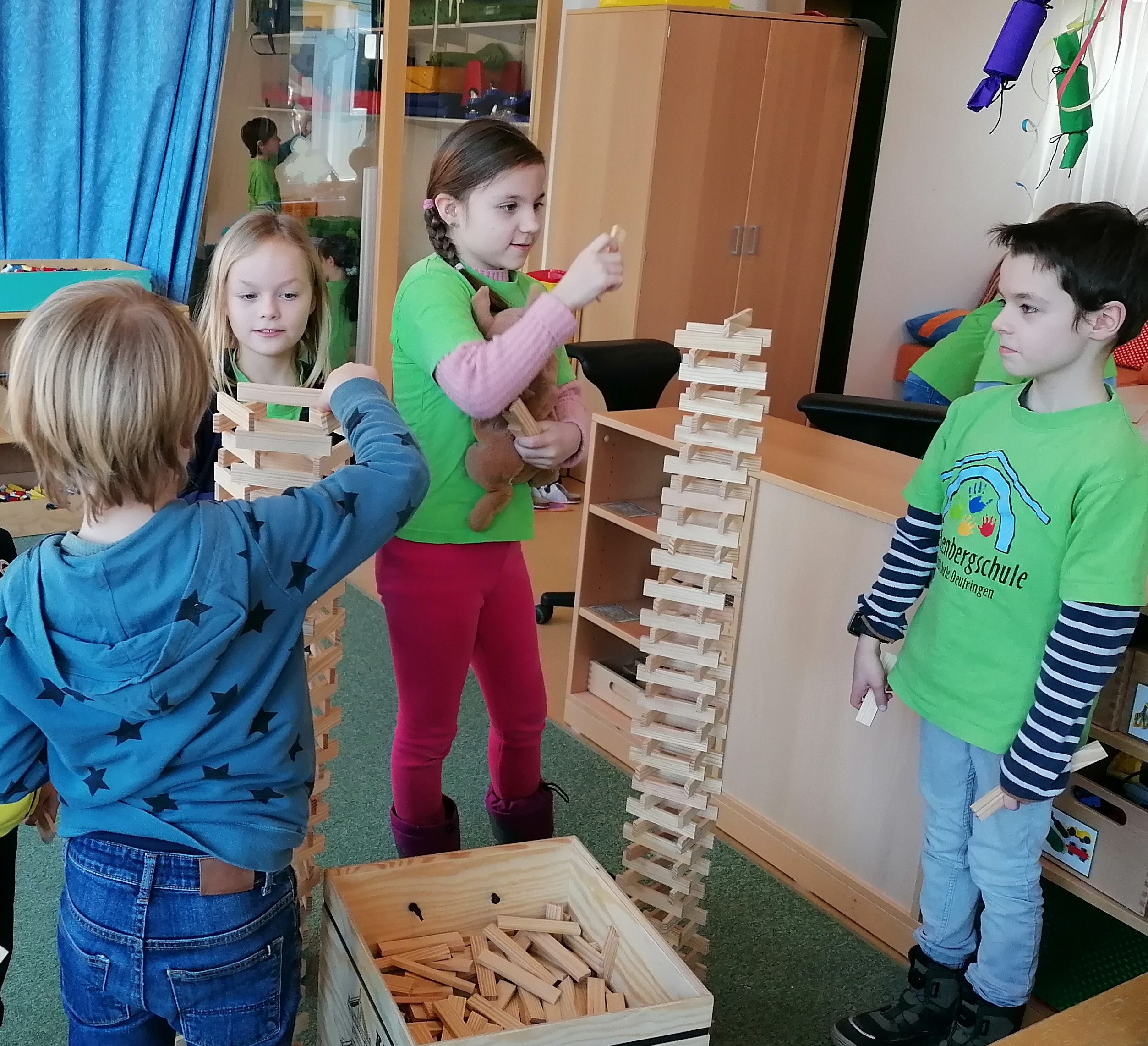 Gemeinsam spielen Schul- und Kindergartenkinder und bauen einen großen Turm.