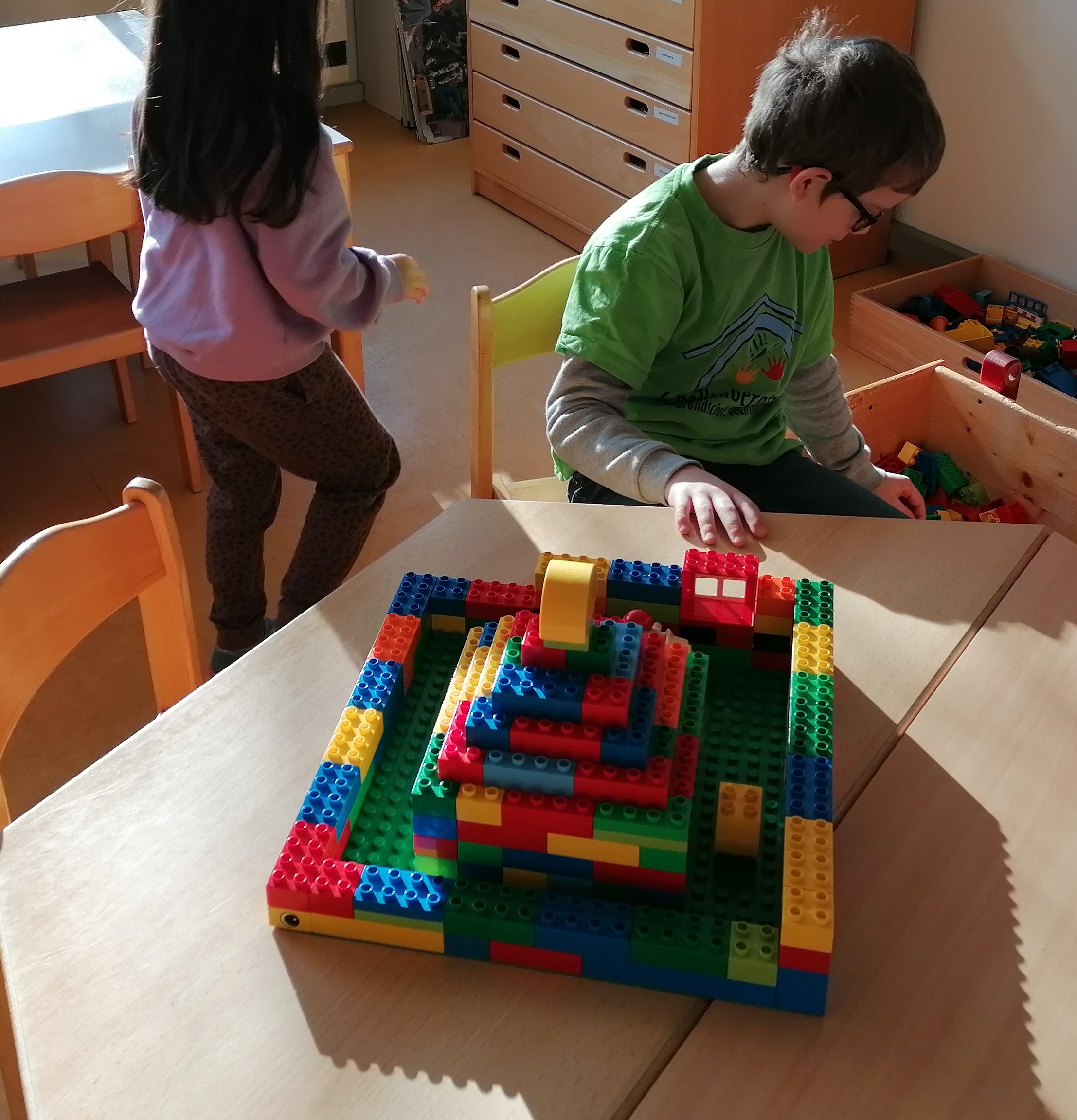 Ein Schuljunge und ein Kindergartenmädchen bauen mit Lego.