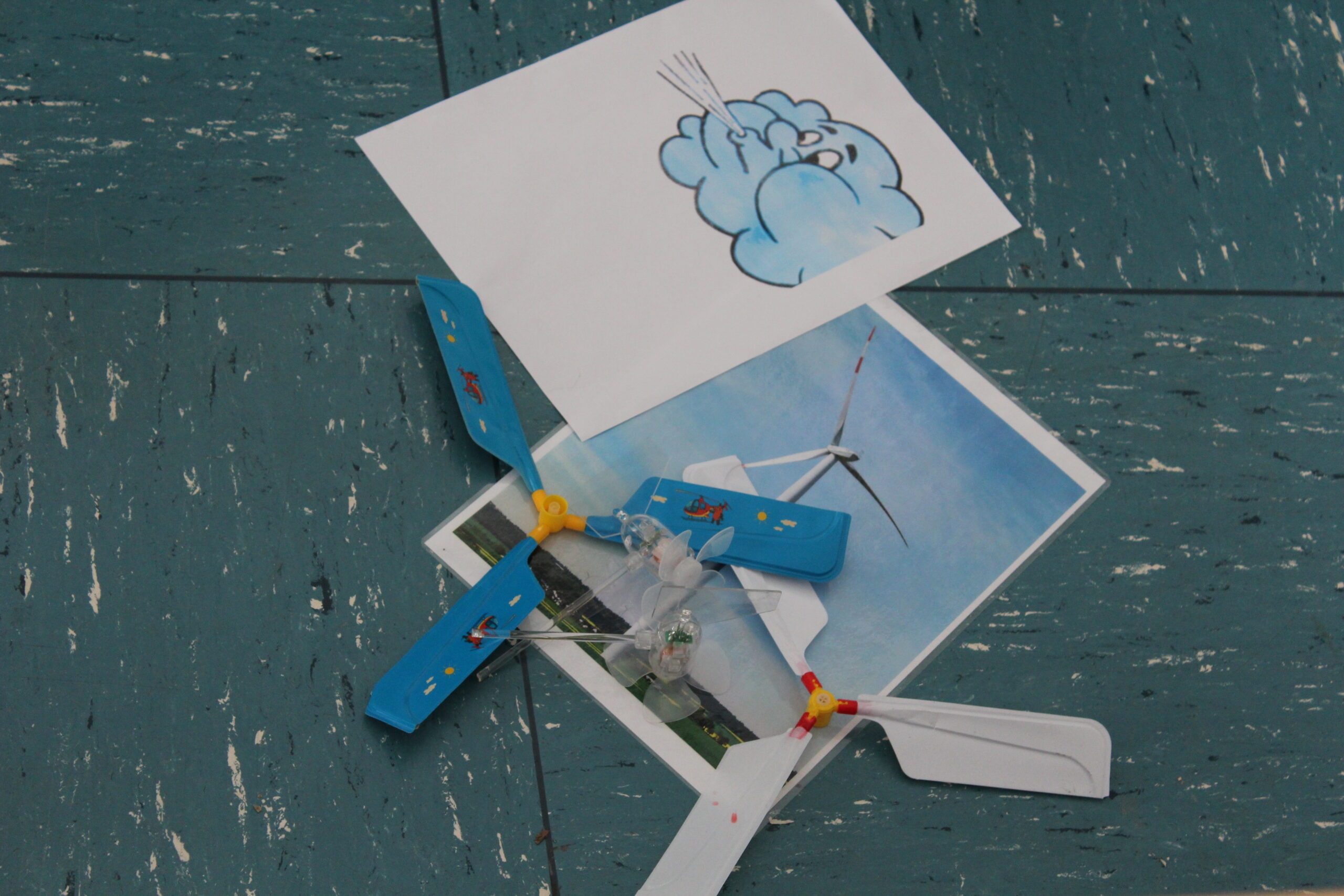 Neben Bilder von Wind und einem Windrad, liegen kleine Propeller.