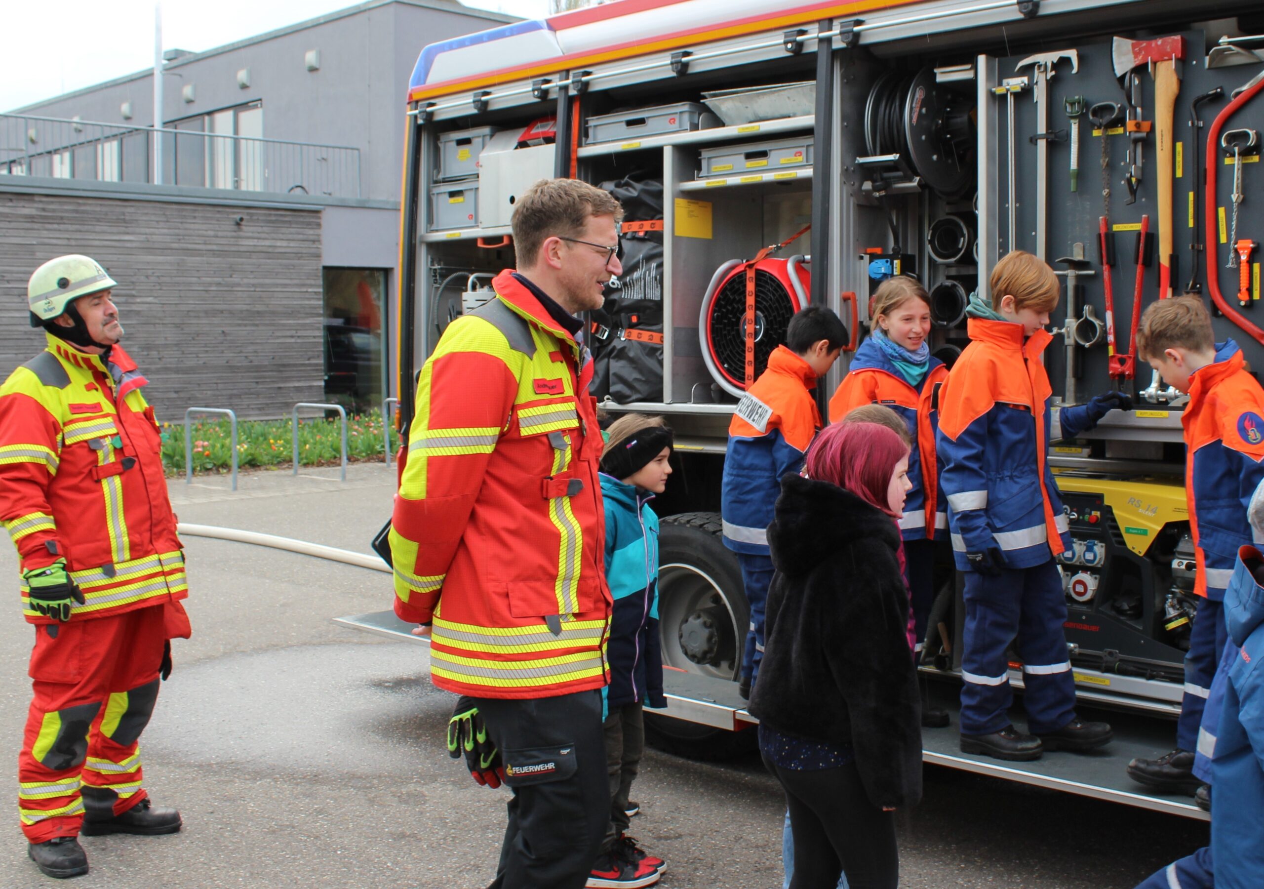 Kinder lernen die Ausstattung eines Feuerwehrautos kennen.
