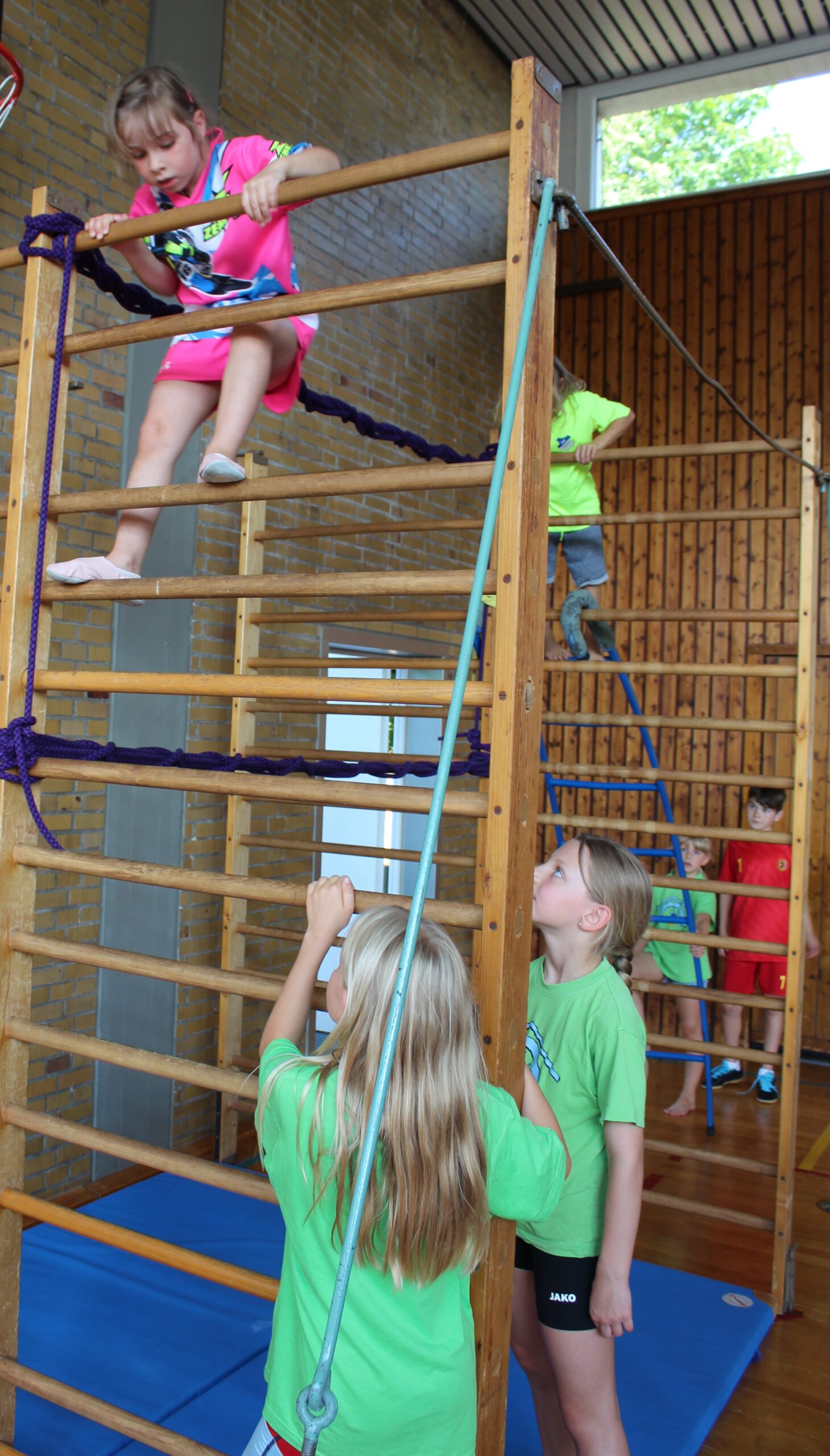 Kinder klettern über die gespannten Seile zwischen den ausgeklappten Sprossenwänden.