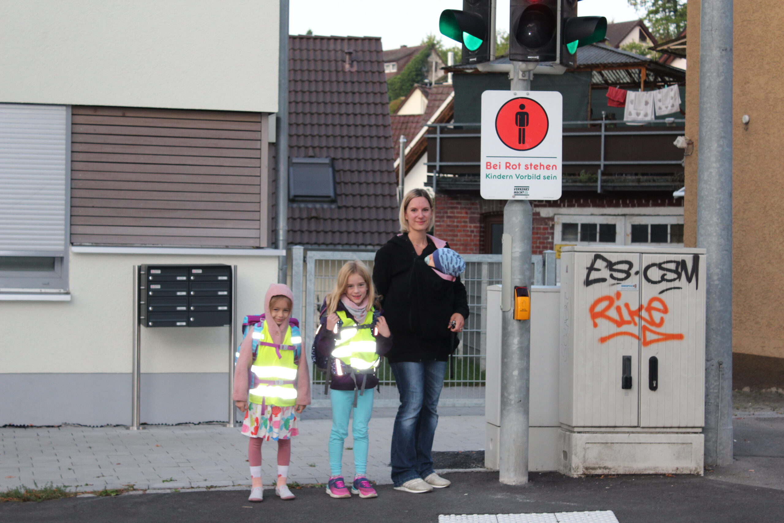 Eine Mutter begleitet zwei Kinder auf ihrem Schulweg.