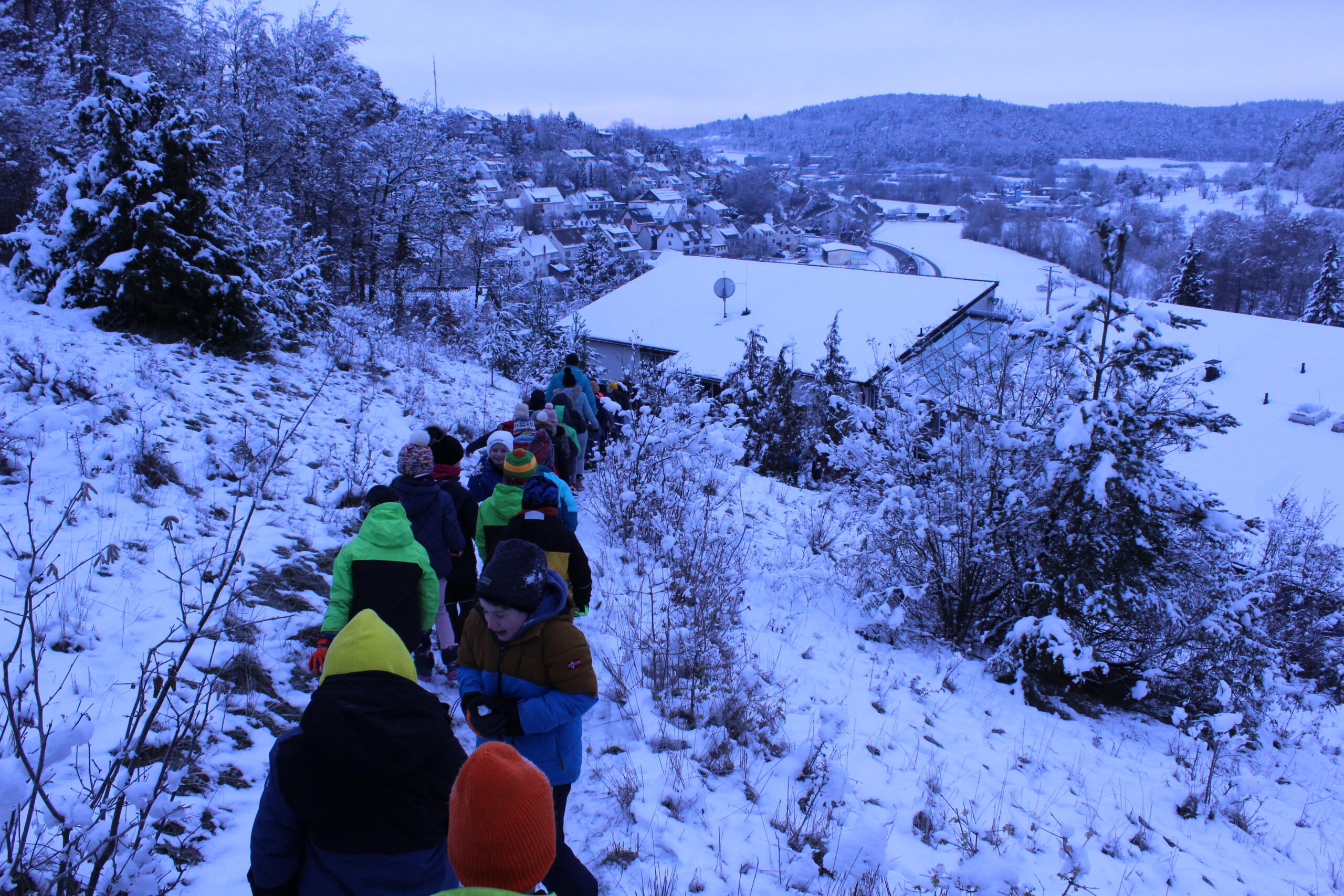 Kinder laufen einen schmalen Weg im Schnee zurück zu einem Schulgebäude.