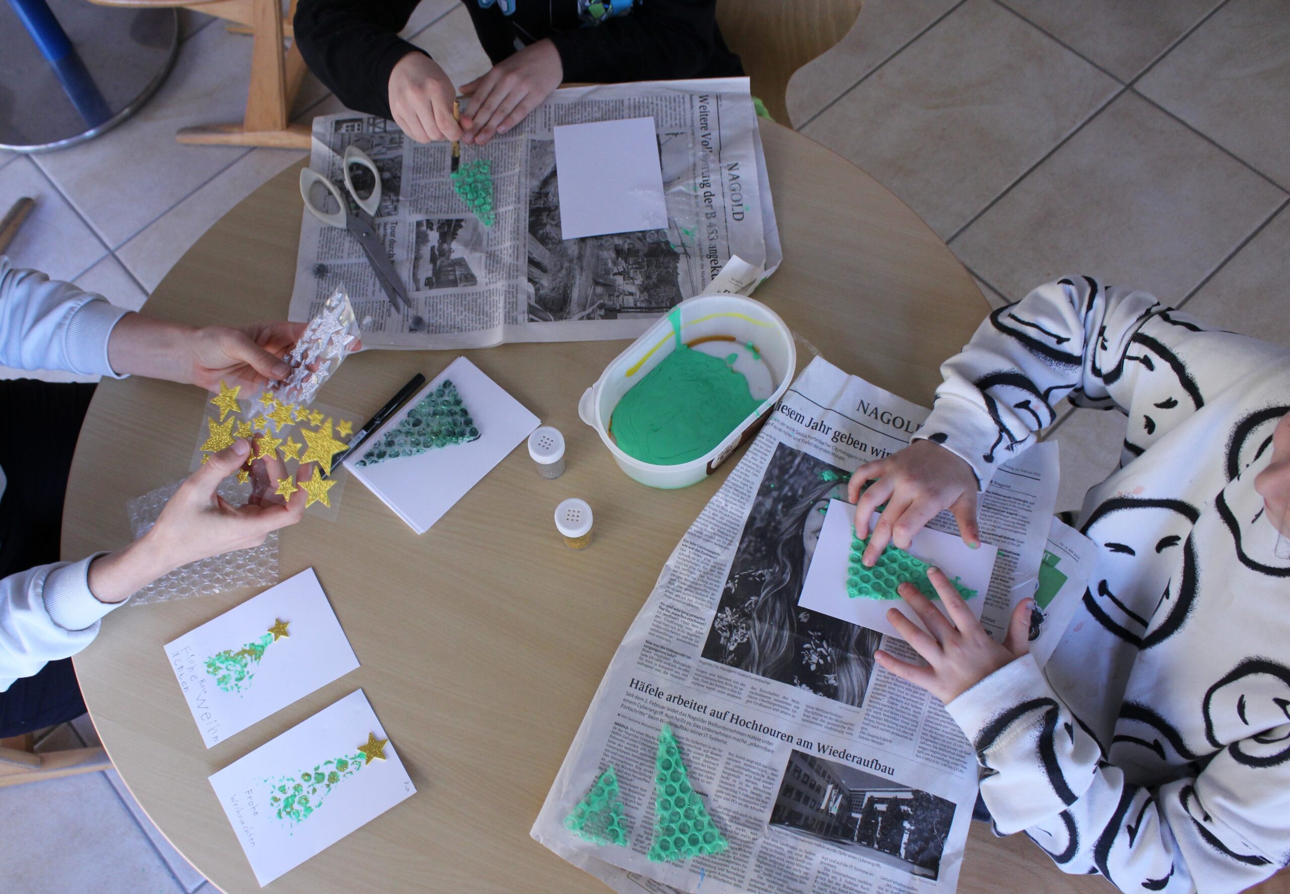 Kinder basteln Weihnachtskarten mit Luftpolsterfolie.