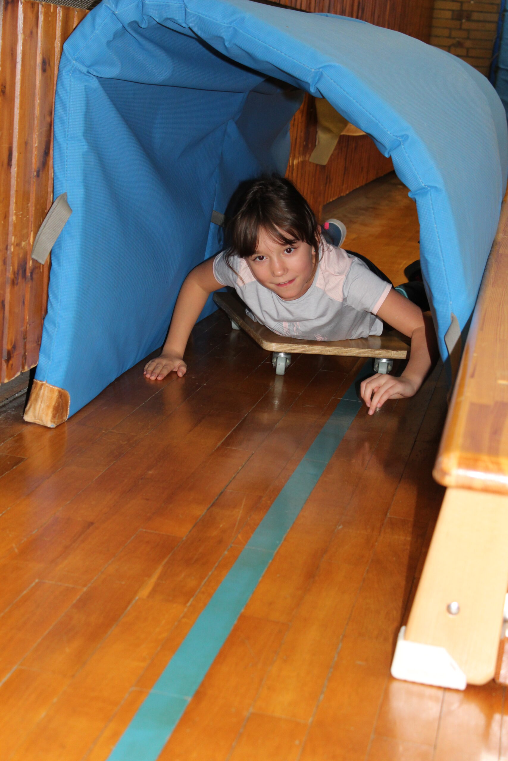 Ein Kind fährt auf einem Rollbrett durch einen Mattentunnel.