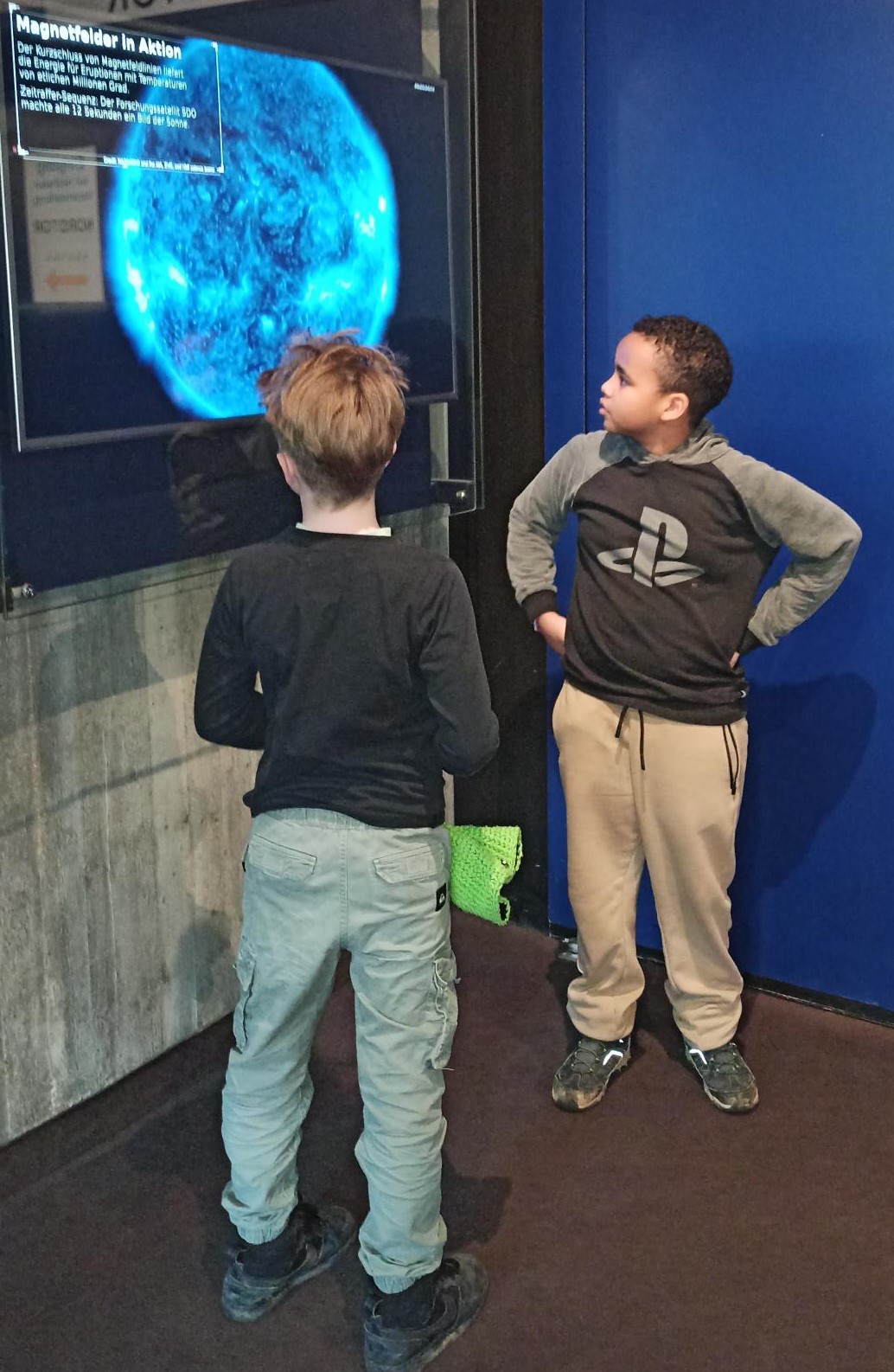 Zwei Kinder stehen vor einer virtuellen Weltkugel im Planetarium.