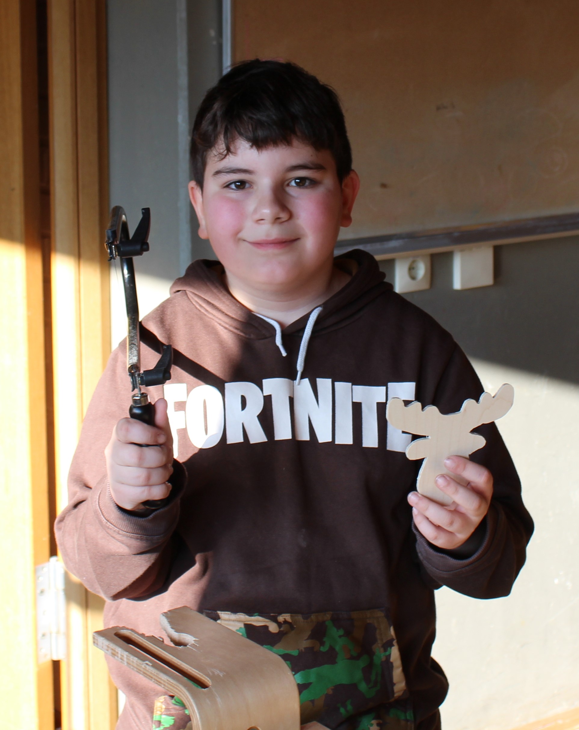 Ein Junge zeigt sein selbst ausgesägte Holzstück.