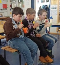 Drei Jungen sitzen auf einer Bank in einem Klassenzimmer und trinken selbstgemixte Kindercocktails.