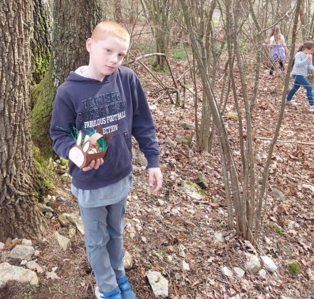Ein Junge hält ein Osternest in den Händen.