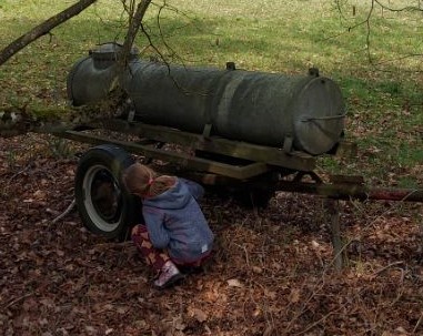 Ein Kind findet ein Osternest an einem Wasserwagen.
