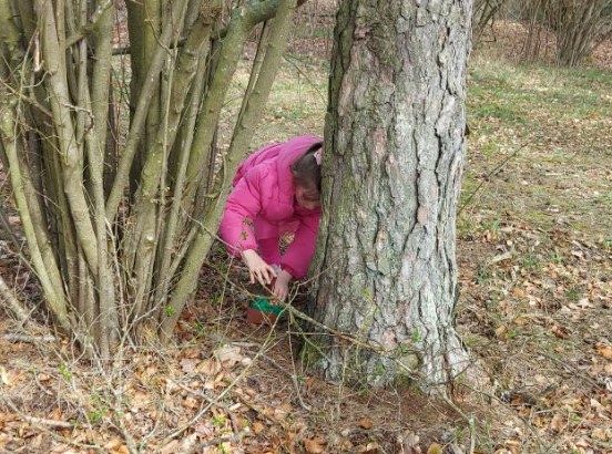 Ein Kind findet ein Osternest an eine Baum.