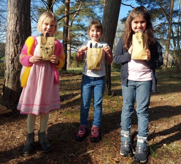 Drei Mädchen zeigen stolz ihre Osternester in die Kamera.