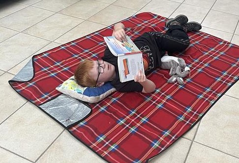 Ein Junge liegt auf einer Matte auf dem Boden und liest.