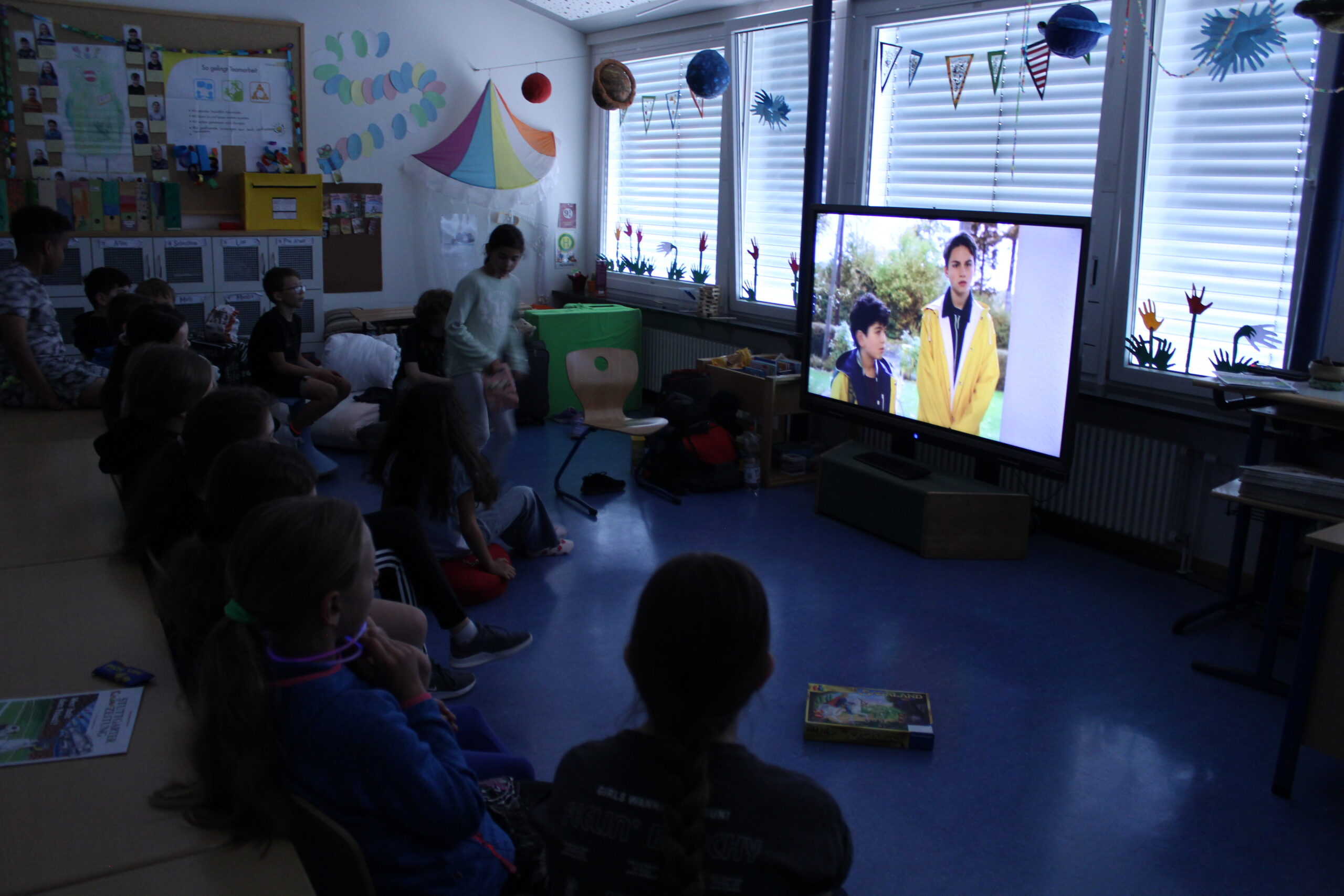 Im Klassenzimmer schauen die Kinder einen Film an.