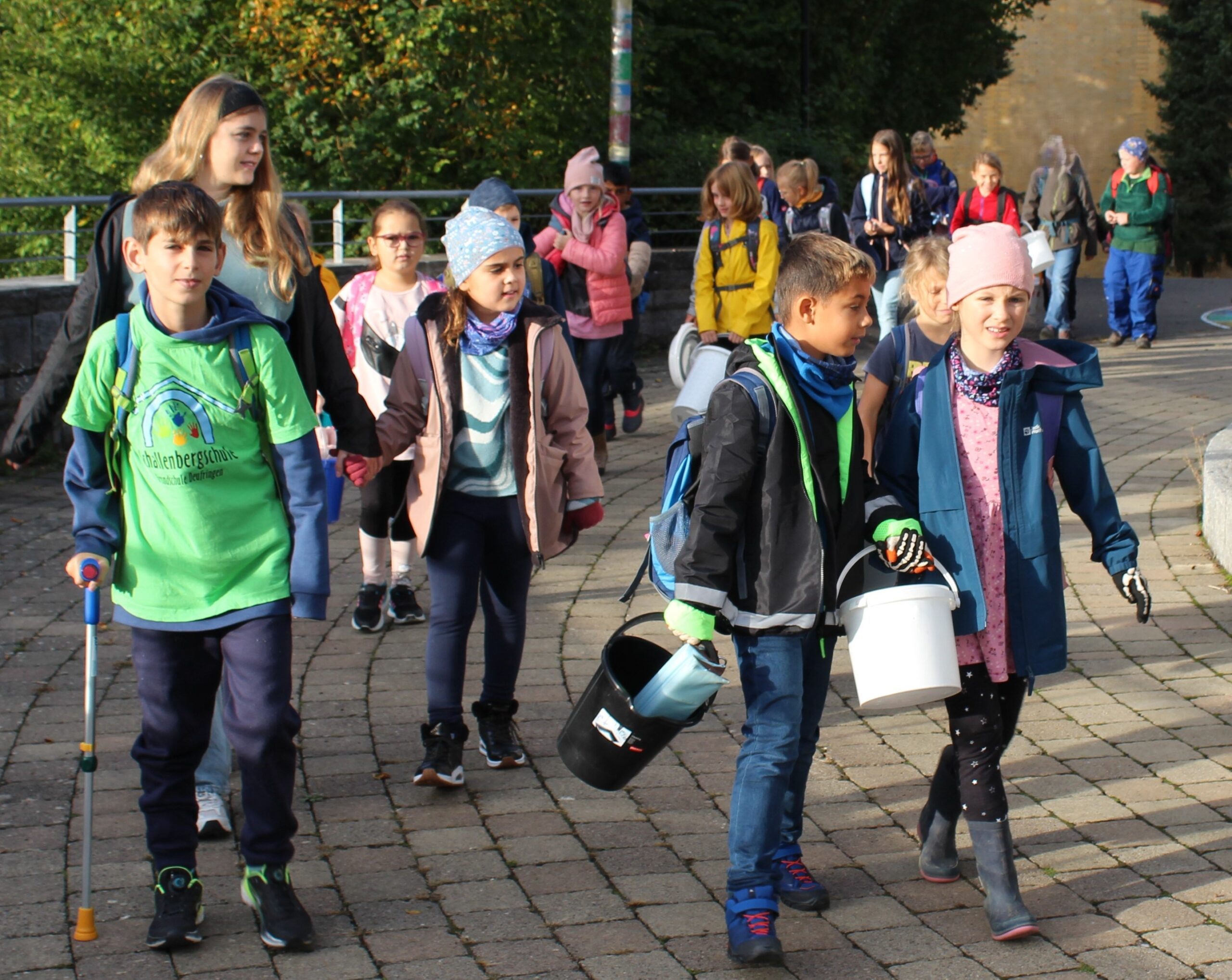 Kinder machen sich auf dem Schulhof auf dem Weg zum Apfelsammeln.