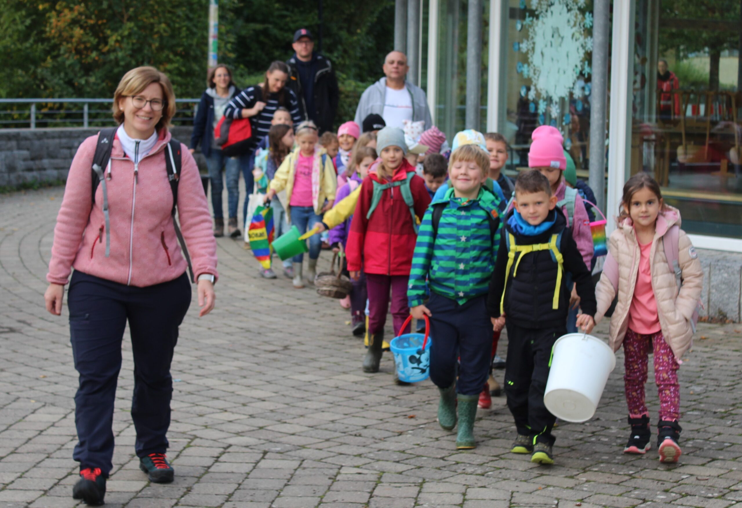 Eine erste Klasse macht sich mit Eimern auf den Weg zum Apfelsammeln.