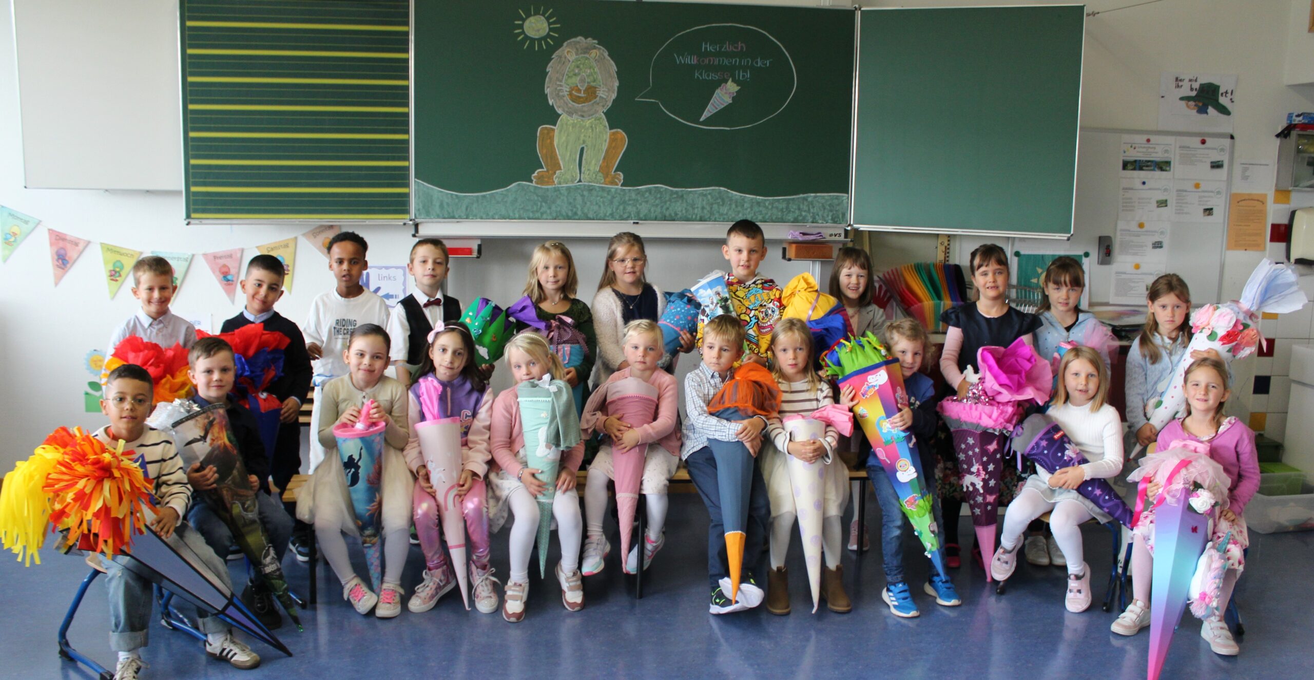 Klassenfoto einer ersten Klasse am ersten Schultag vor der Tafel mit Schultüten.