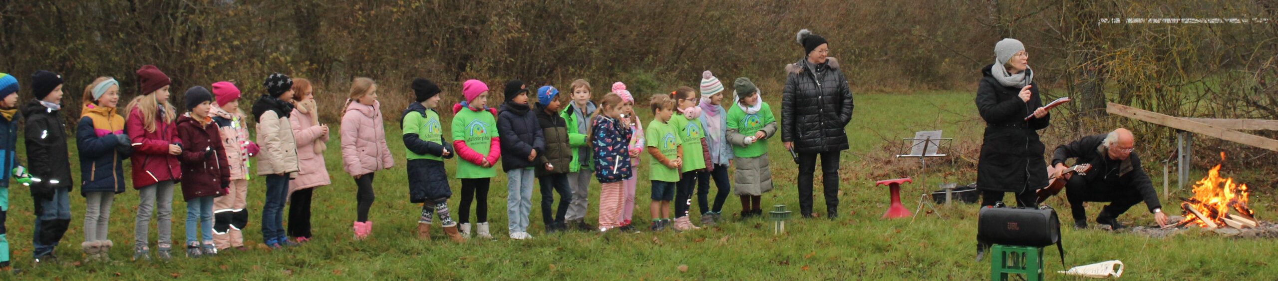 Eine Klasse steht mit ihrer Lehrerin auf einer Wiese beim Adventsingen.