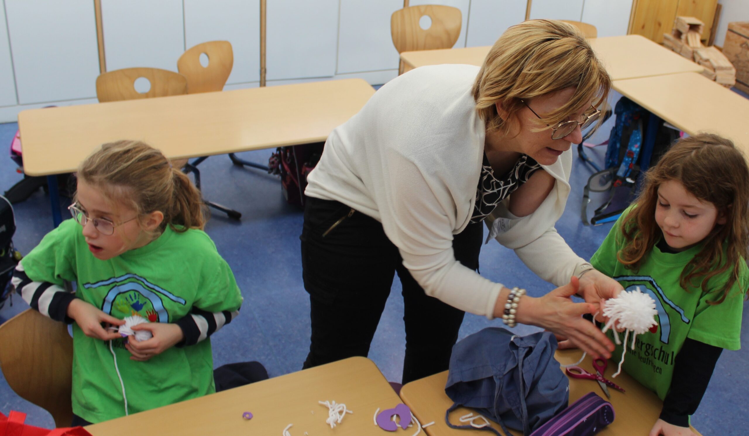 Eine Lehrerin zeigt gerade einem Kind den nächsten Bastelschritt.