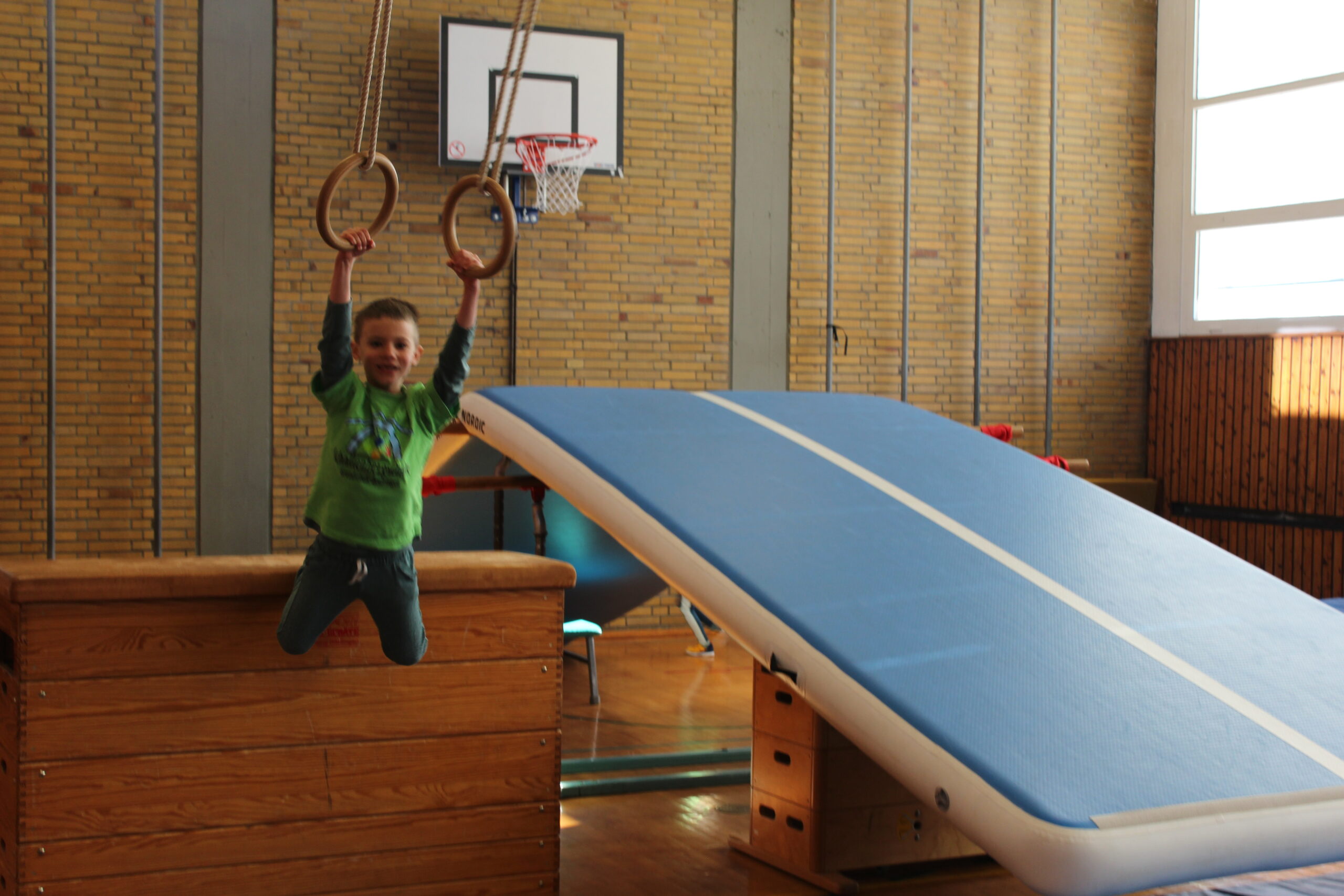 Ein Kind schwingt an den Ringen in der Sporthalle.