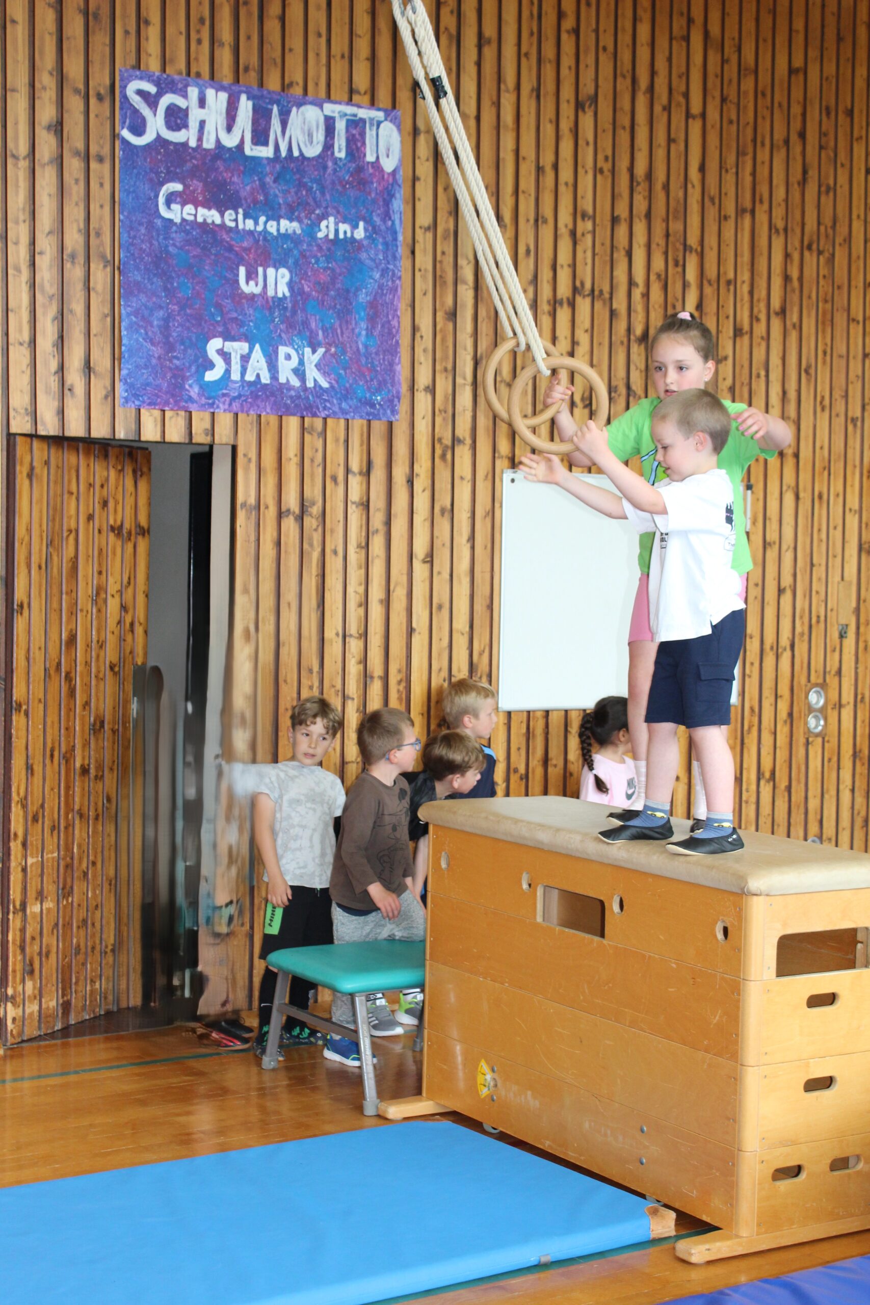 Eine Drittklässlerin hilft einem Kindergartenkind bei den Ringen.