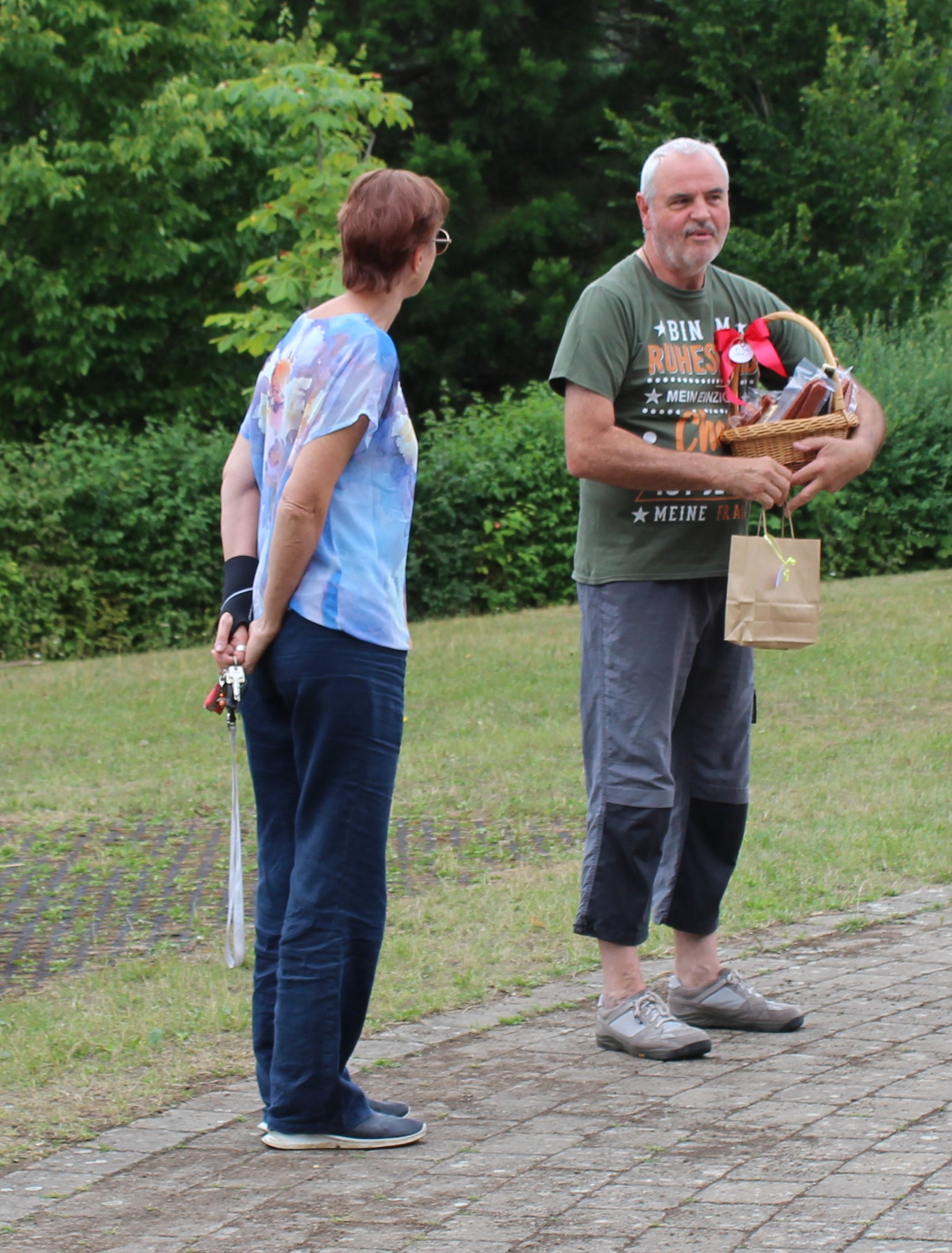 Frau Sonntag und Herr Wosnitzka stehen nebeneinander, Herr Wosnitzka hält einen Präsentkorb