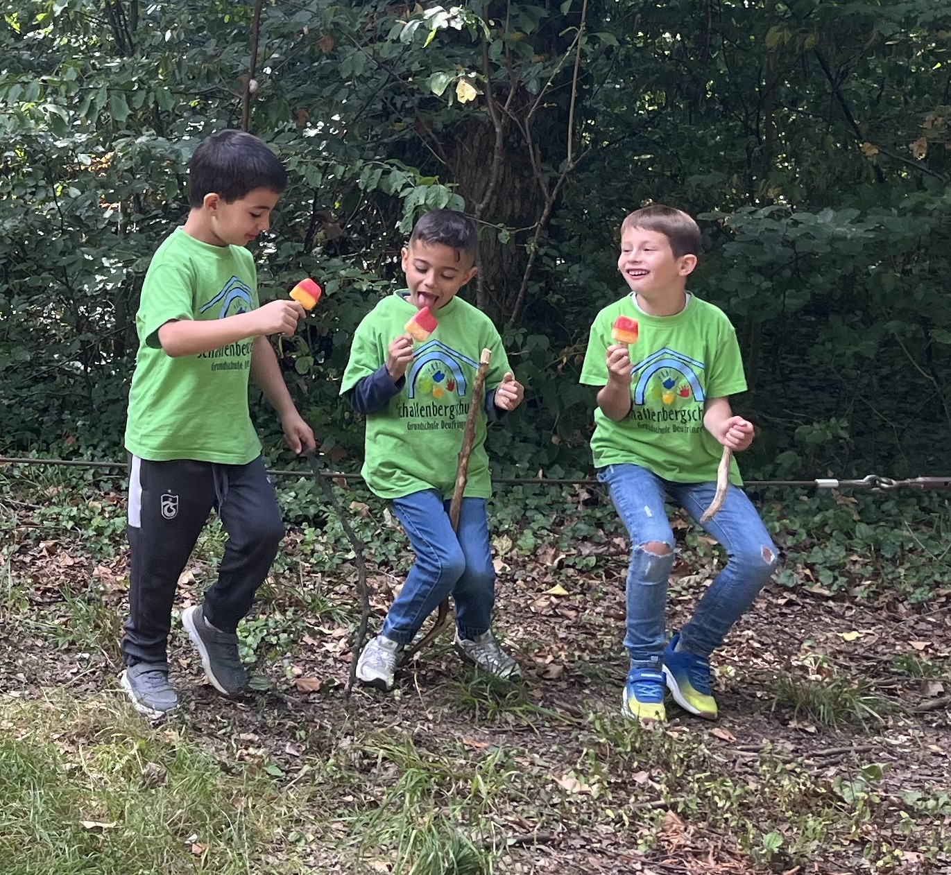 drei Jungs sitzen auf einem gespannten Seil im Wald, sie essen ein Eis