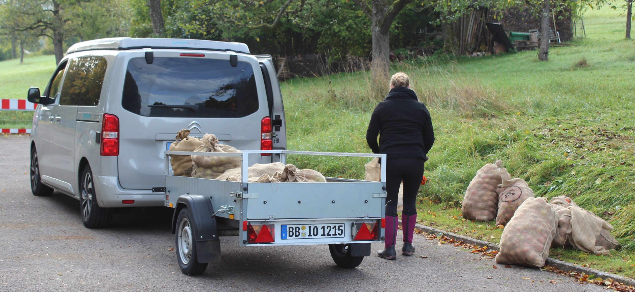 Die Elternvertreterin und Fördervereinsvorsitzende lädt gerade gefüllte Säcke mit Äpfeln auf einen Anhänger.