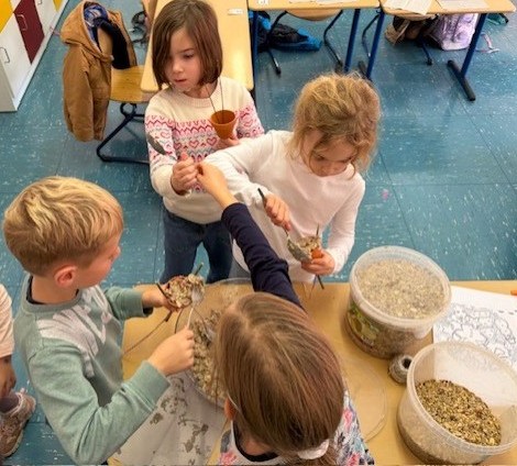 Kinder füllen Tontöpfchen mit Vogelfutter und Fett.