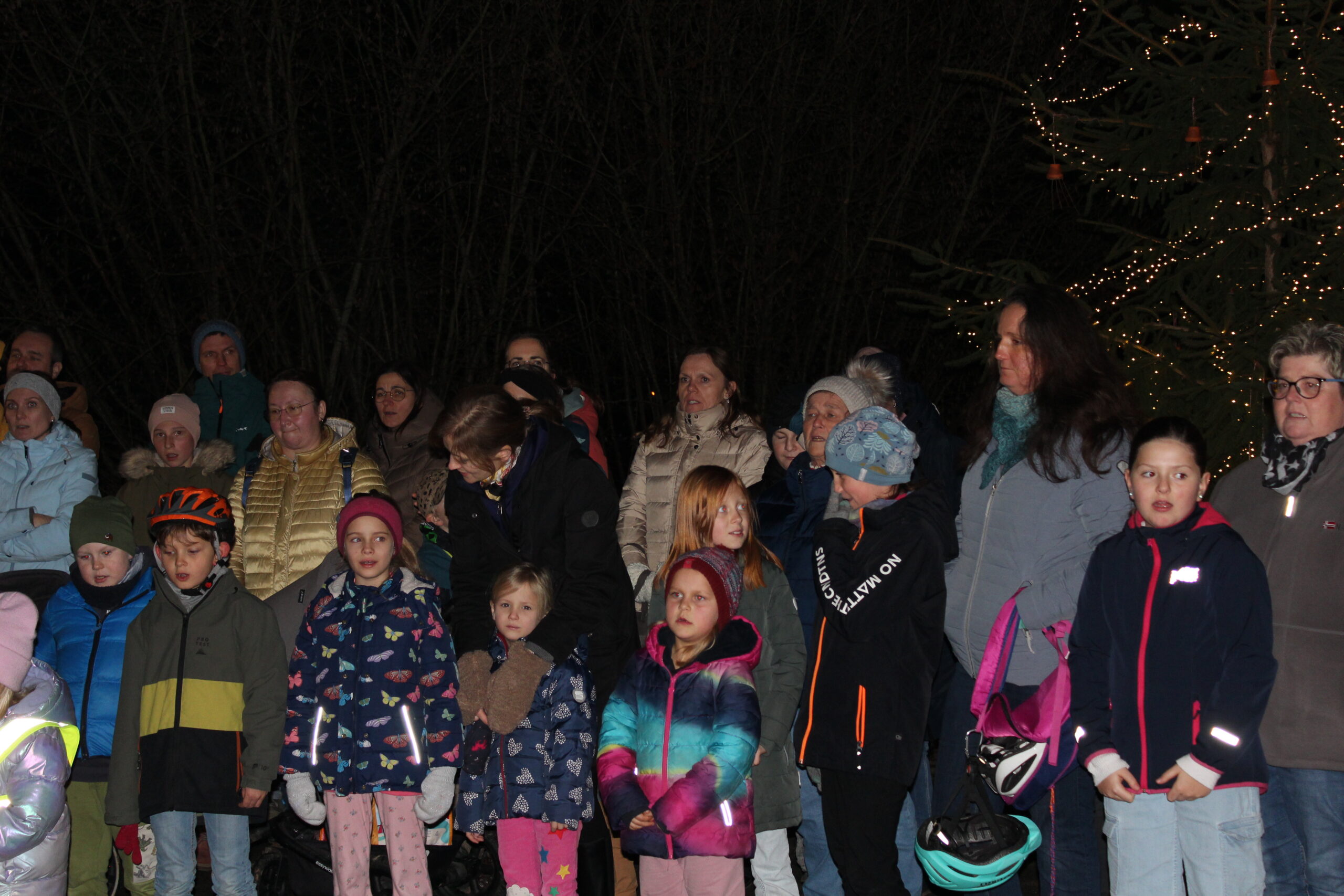 Eltern, Kinder und Gäste treffen sich zum lebendigen Adventskalender vor der Schule.