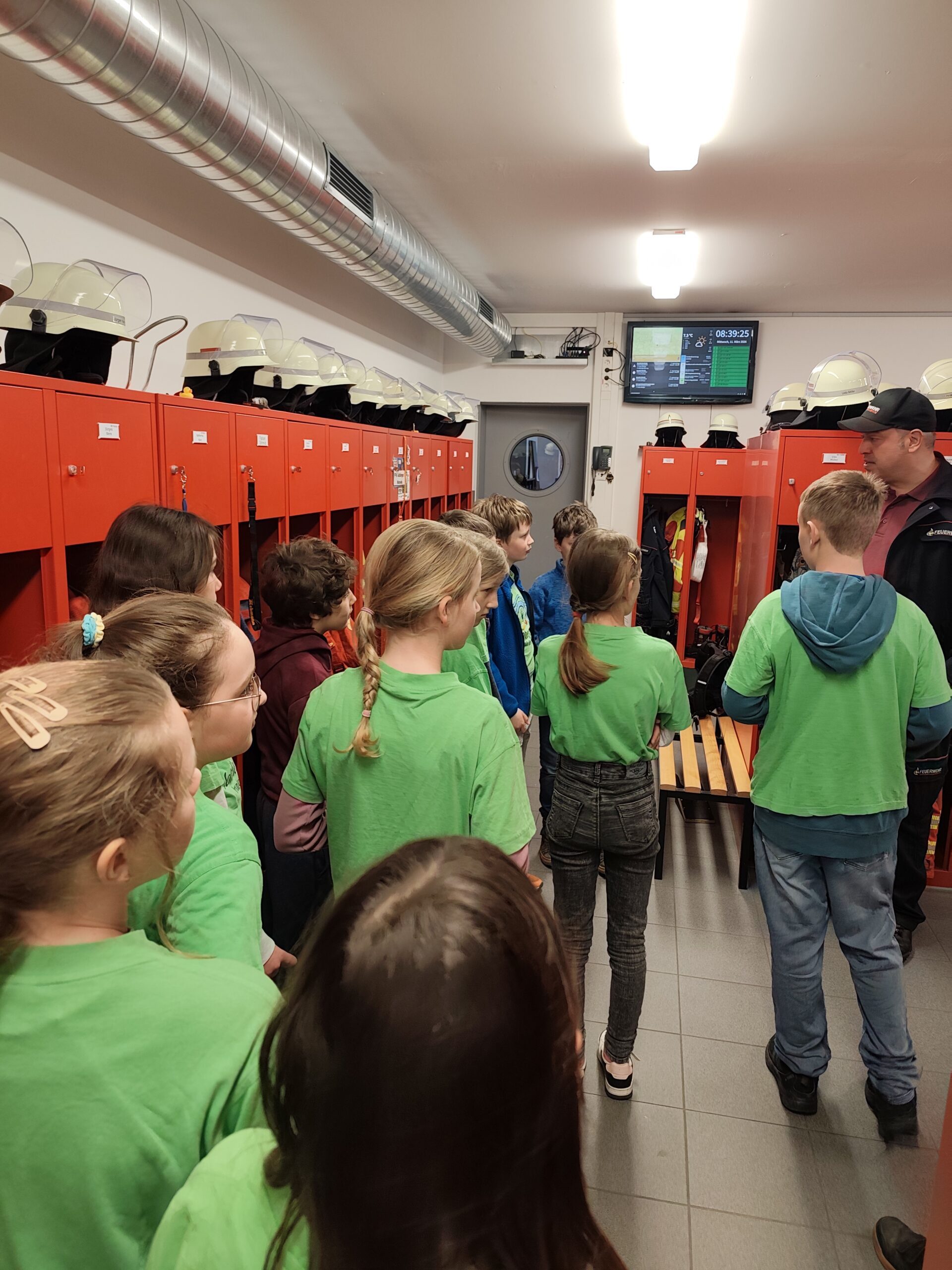 Eine Klasse ist in dem Umkleideraum der Feuerwehr zur Besichtigung.