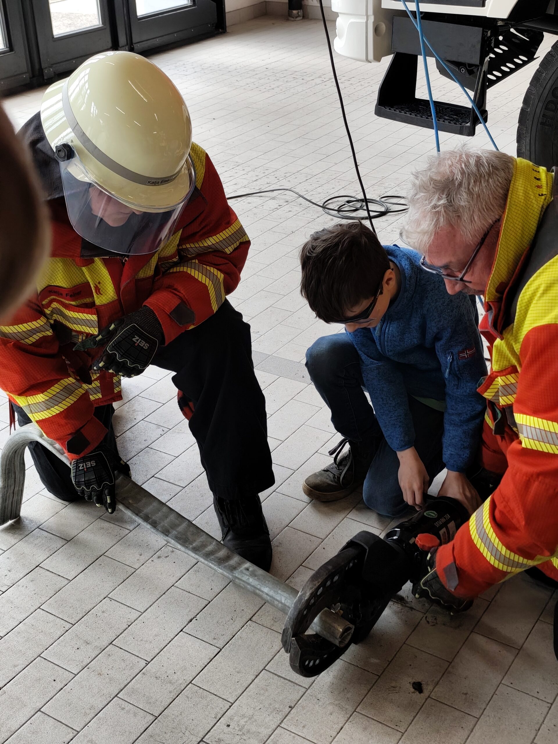 Ein Kind darf bei der Feuerwehr bei einem schweren Gerät mithelfen.
