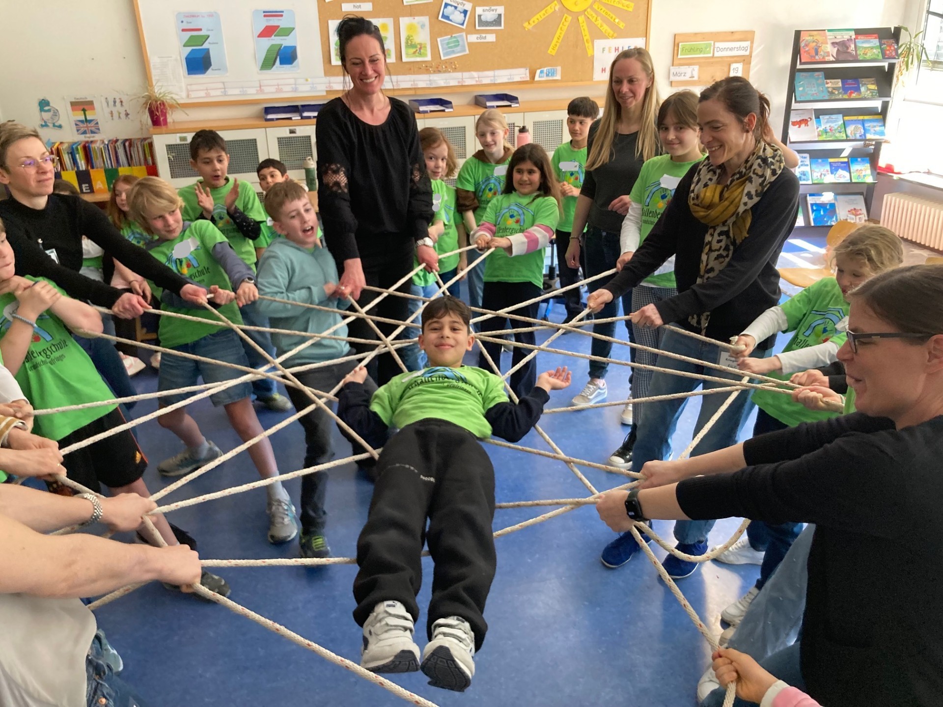 Aus guten Worten für ein Kind wird mit einem Seil ein Netz gespannt, auf dem ein Kind liegen darf und von der Gemeinschaft getragen wird.