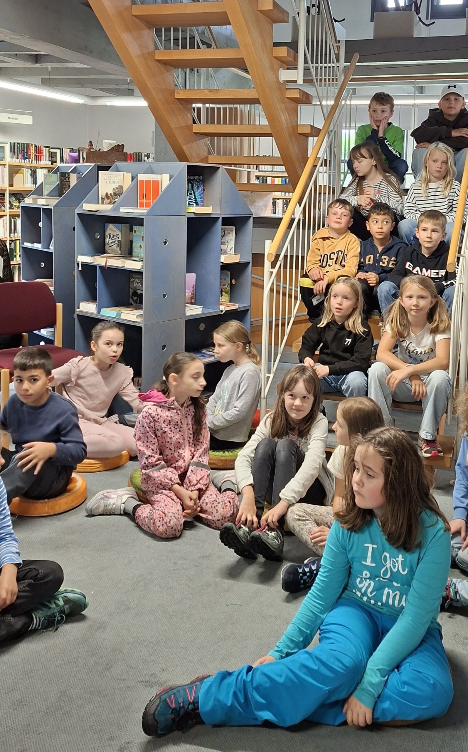 Zweitklässler sitzen in der Ortsbücherei auf der Treppe für ein Klassenfoto.