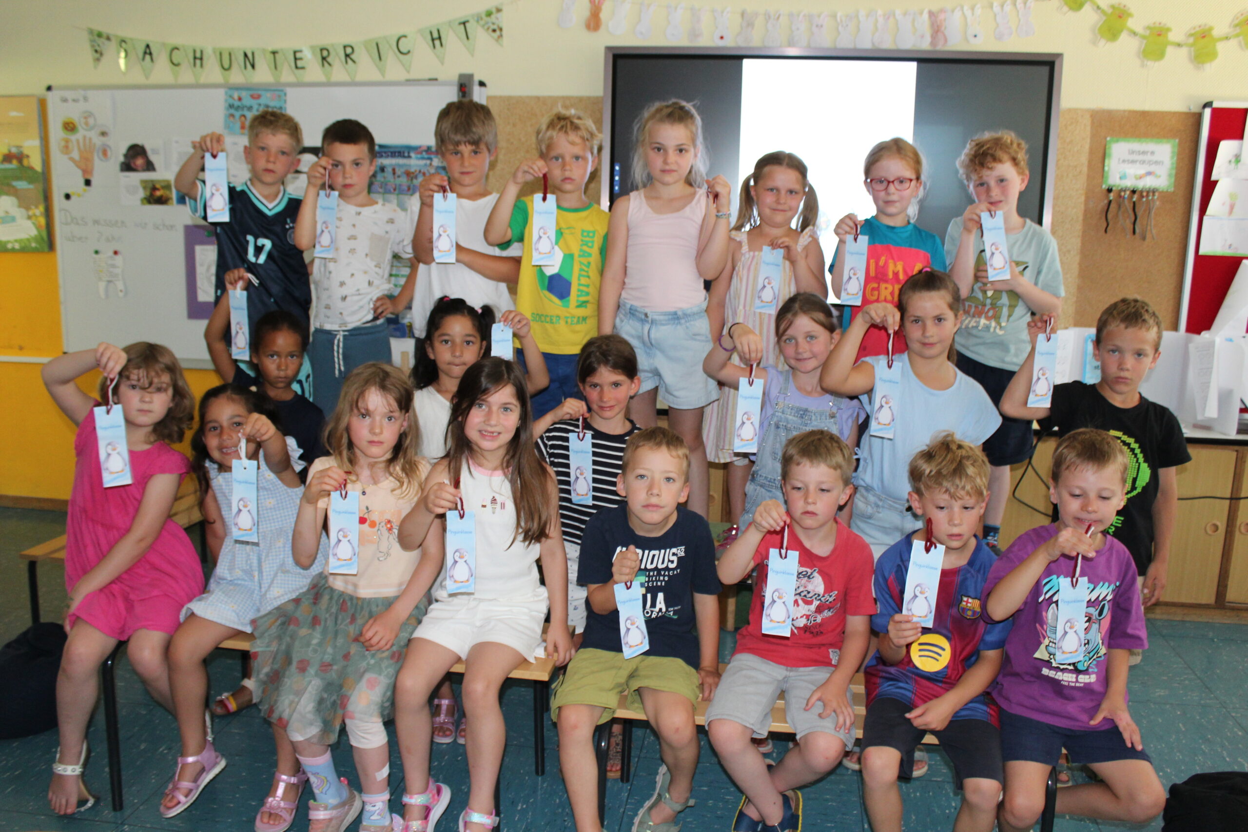 Die Erstklässler haben zusammen mit den zukünftigen Schulkindern ein Lesezeichen gebastelt und zeigen das.