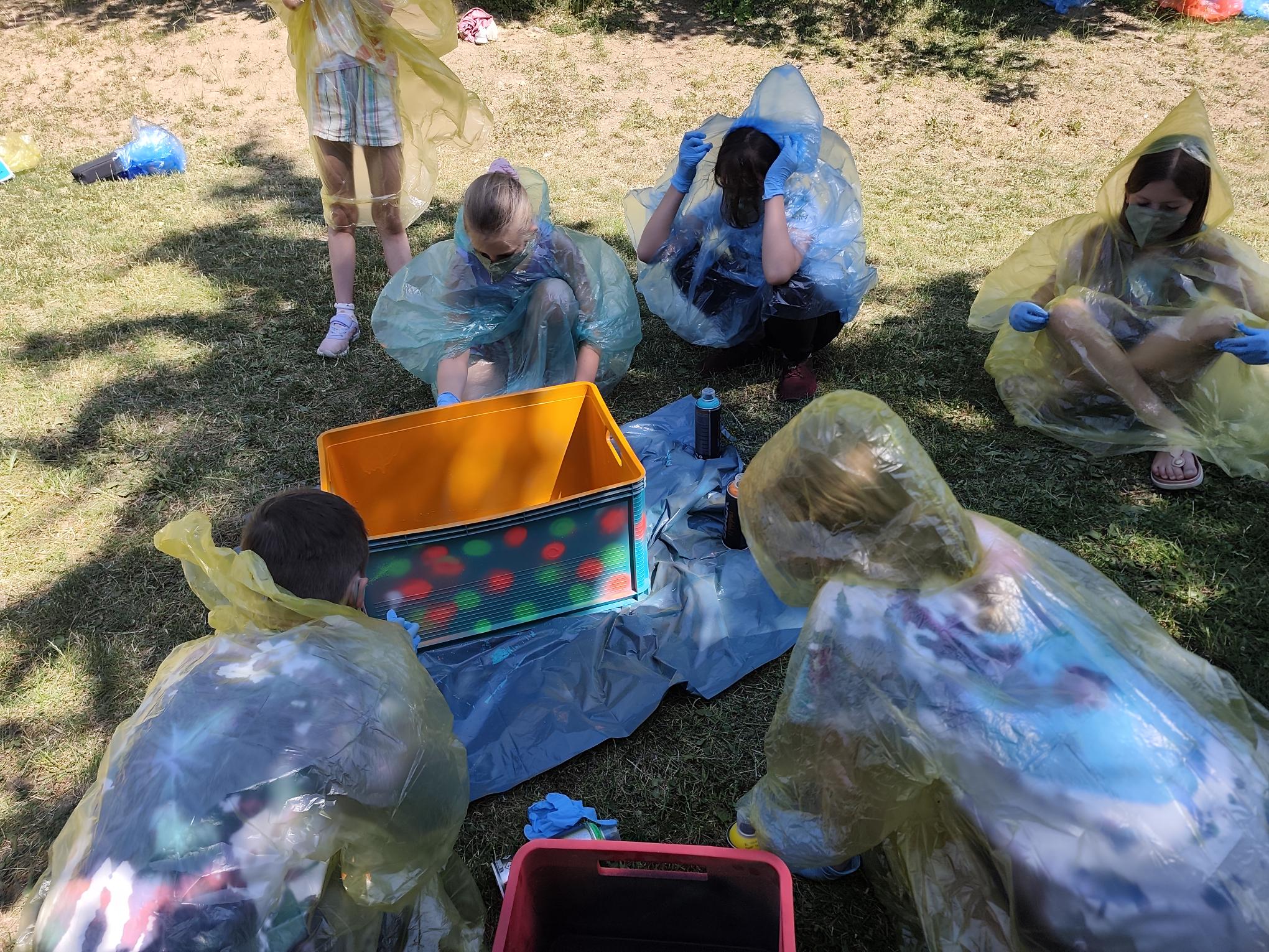 Hier sieht man, wie die Kinder in Schutzkleidung die Pausenkisten besprühten.