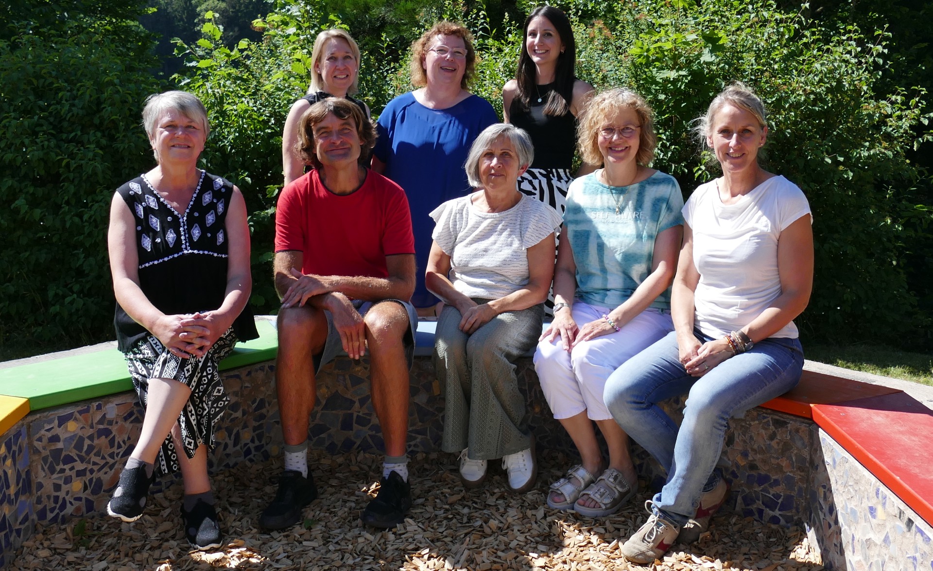Das Team der Kernzeitbetreuung sitzt im Kreis auf dem Pausenhof.