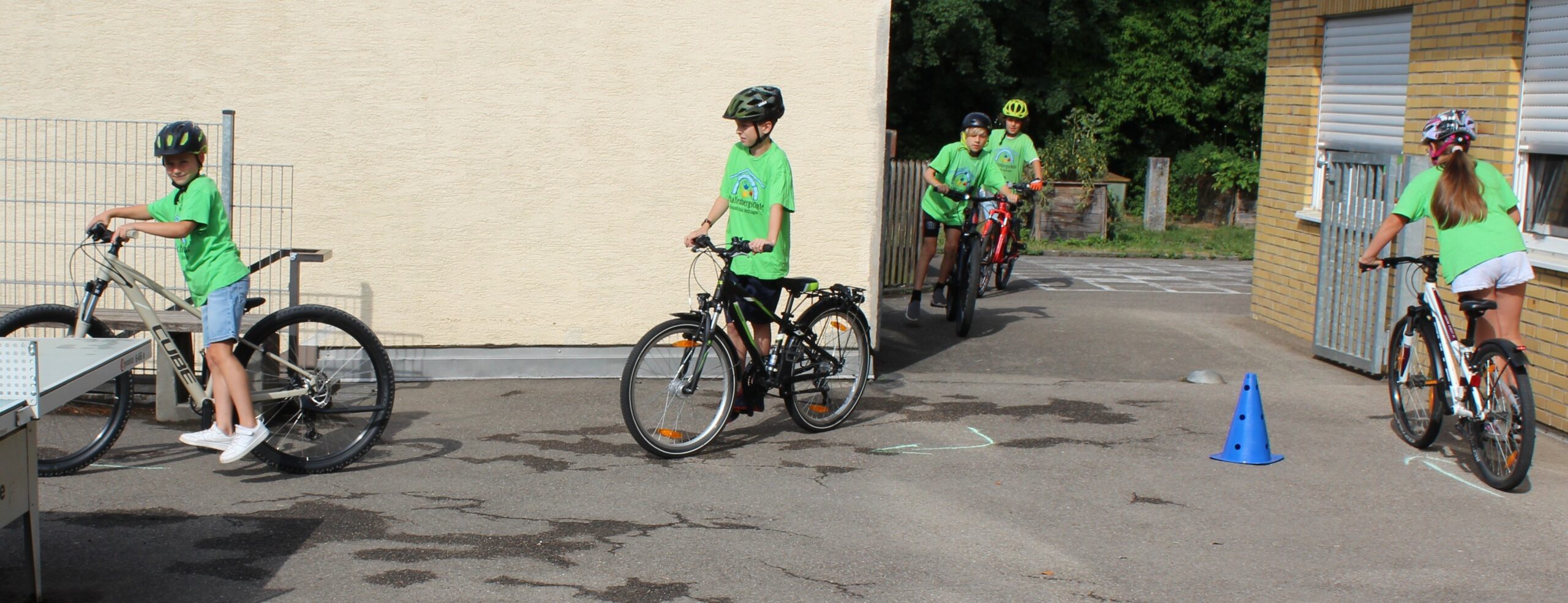 Kinder stehen mit einem Fuß auf dem Pedal und fahren so mit dem Rad, als wäre es ein Roller.