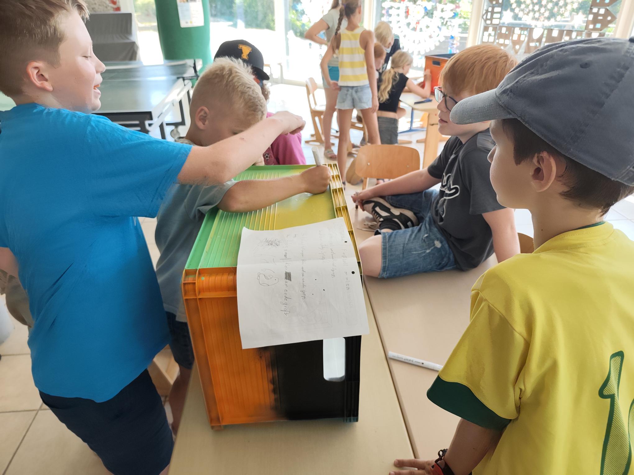 Kinder bemalen die Pausenkisten.