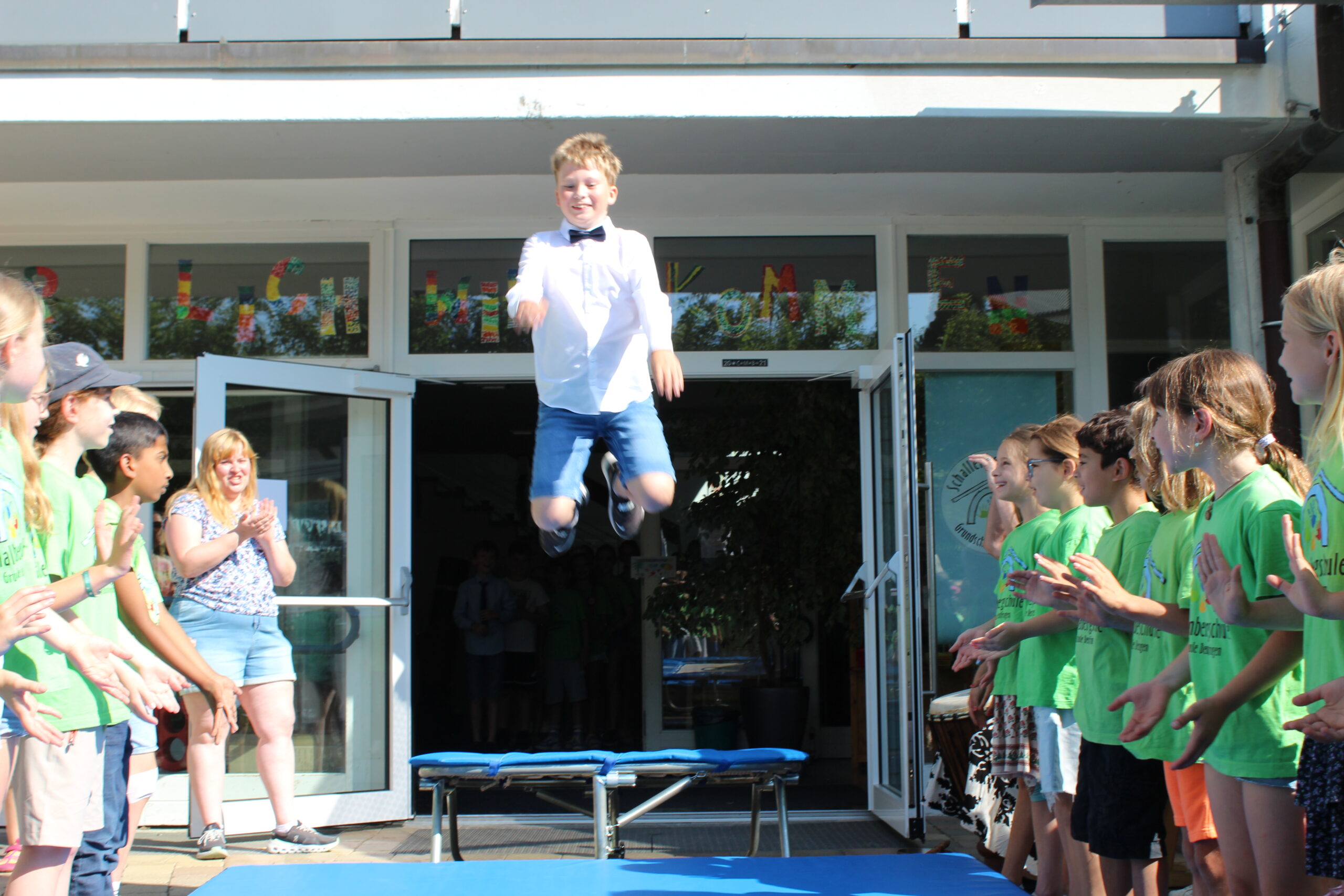 Ein Junge springt in ein Trampolin vor der Schultüre und "fliegt" somit aus der Schule.