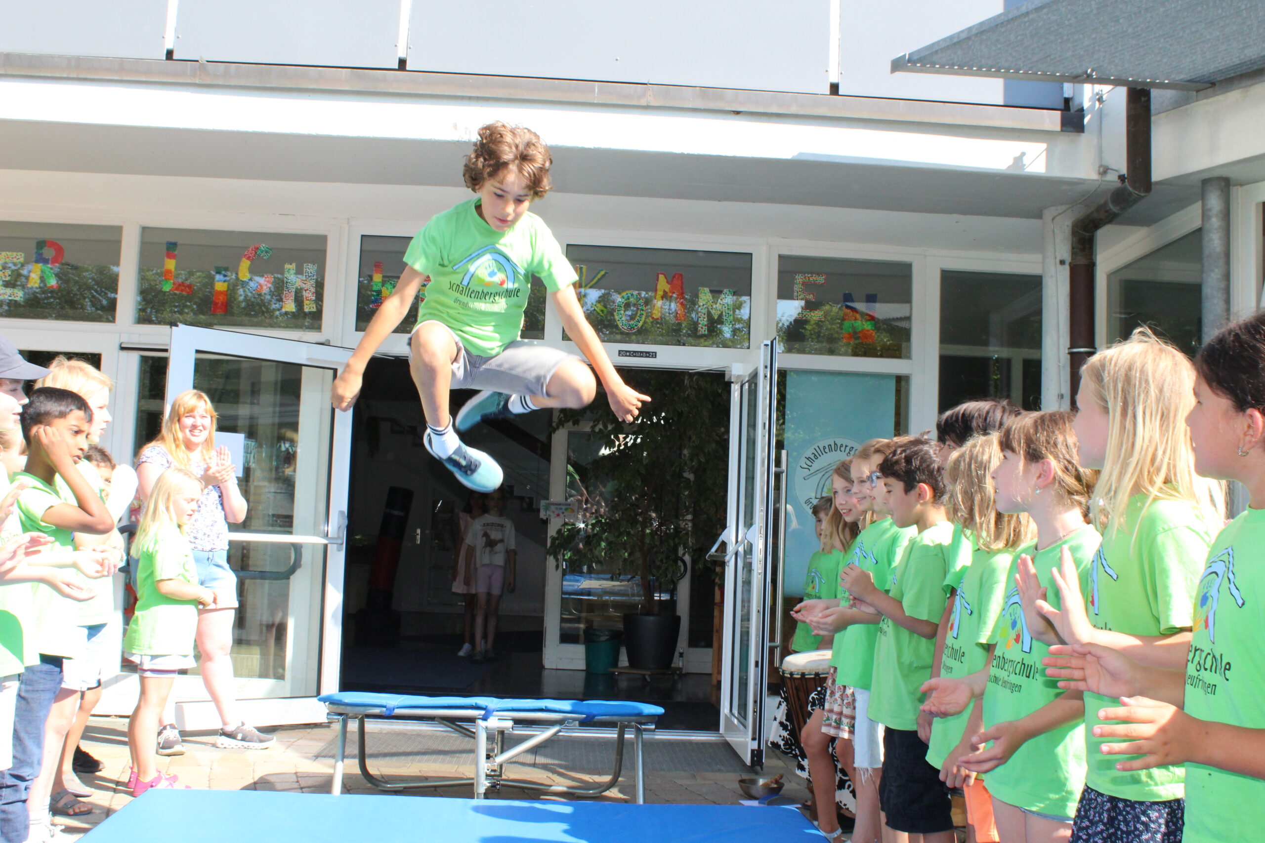 Ein Junge springt in ein Trampolin vor der Schultüre und "fliegt" somit aus der Schule.