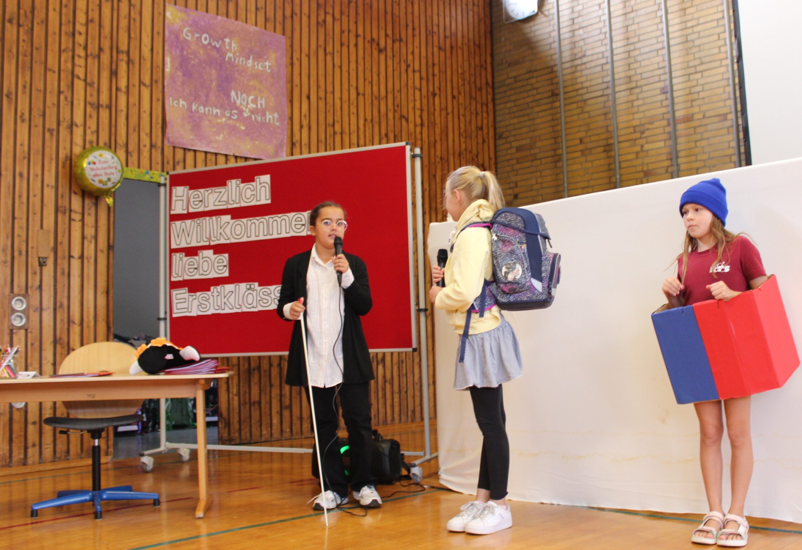 Schulkinder spielen im Theaterstück ein Schulkind liest etwas der Lehrerin vor.